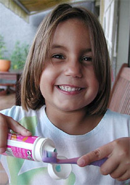 Una niña con dientes de leche se prepara para la higiene bucal.