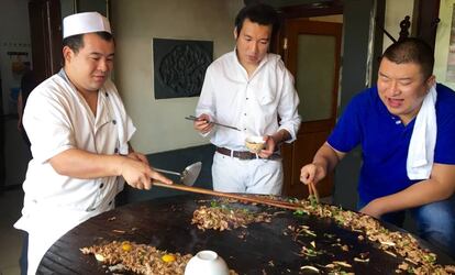 Shao Bao y sus dos cocineros durantes los toques finales de la barbacoa.