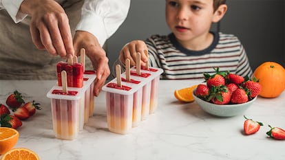 Un niños con un adulto haciendo helados en moldes.