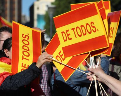 Reparto de banderas de España durante la concentración que se ha convocado este sábado en la plaza de Colón (Madrid).