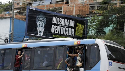 Passageiros circulam em ônibus lotado nesta terça-feira, no Rio de Janeiro, ao lado de outdoor crítico a Jair Bolsonaro.