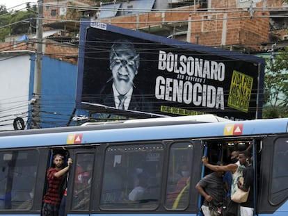 Passageiros circulam em ônibus lotado nesta terça-feira, no Rio de Janeiro, ao lado de outdoor crítico a Jair Bolsonaro.