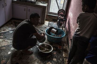Raju Lama, el hombre del matrimonio que se encarga de los niños en la casa de acogida, lava los platos, con la ayuda de los niños.