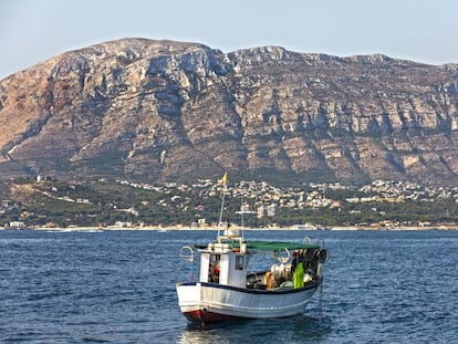 Un barco en la bahía de Dénia y, al fondo, el macizo de Montgó.