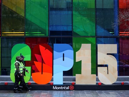 Agentes de policía pasan frente a uno de los carteles de la COP15, que se ha celebrado en Montreal (Canadá).