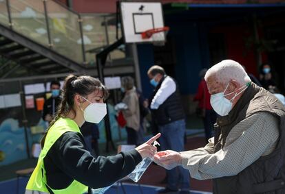 Las medidas de protección contra el coronavirus están muy presentes en los centros de votación. En la imagen, un hombre desinfecta sus manos con gel hidroalcohólico antes de acceder a un colegio electoral en Madrid.