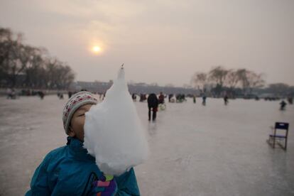 Un niño disfruta de un dulce en el lago congelado Houhai antes del Año Nuevo Lunar, en Pekín (China).