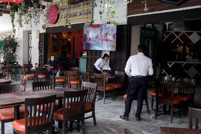 Los meseros de un restaurante sin clientes en el centro de Atlixco limpian la ceniza de las mesas.