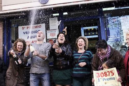 Agraciados por la Loter&iacute;a celebran su suerte en la puerta de una administraci&oacute;n en Alcorc&oacute;n (Madrid).