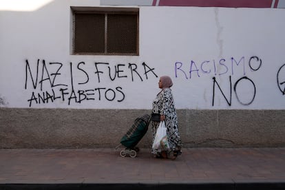 Una mujer camina por una calle del barrio de San Antonio junto a una pintada.