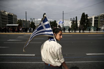 Una niña sostiene una bandera griega antes de un desfile estudiantil en Atenas durante las celebraciones del Día de la Independencia de Grecia.