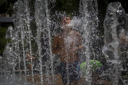 Un nen es refresca en una font al barri d'Horta, a Barcelona.