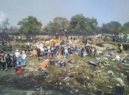 Bomberos y sanitarios, entre los restos del avión de Spanair que se estrelló en Barajas.