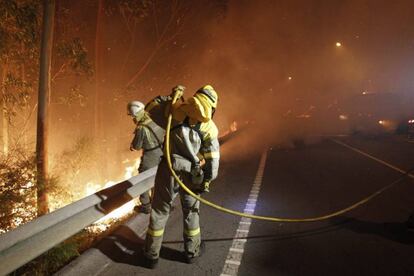 Dos bomberos trabajan en la extinción del incendio de Ribeira en 2013.