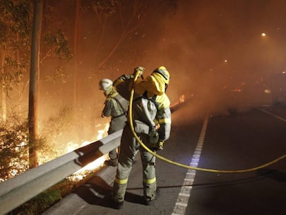 Dos bomberos trabajan en la extinción del incendio de Ribeira en 2013.