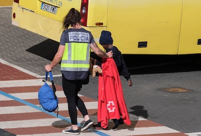 Una policía acompaña a un menor rescatado de un cayuco a su llegada al puerto de Santa Cruz de Tenerife el pasado viernes.