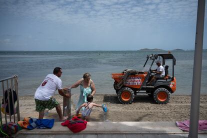Una excavadora recoge algas en la playa de Los Urrutias.