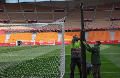 Dos operarios trabajan junto a una portería en el estadio de La Cartuja en Sevilla, este lunes.