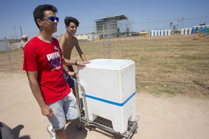 Dos jóvenes transportan una nevera, en el camping del festival Arenal Sound, en Burriana, Castellón.
