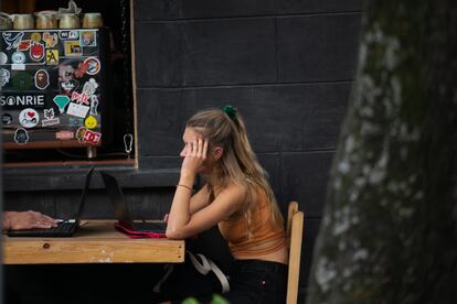 Una joven extranjera utiliza su computadora portatil en un café en la calle de de Orizaba, en Ciudad de México