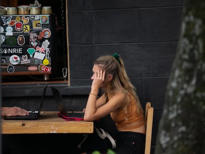 Una joven extranjera utiliza su computadora portatil en un café en la calle de de Orizaba, en Ciudad de México