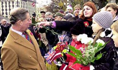 Carlos de Inglaterra, en el momento en que saluda a la gente, que aprovechó la pelirroja Alina para lanzarle un ramo de claveles como protesta por la participación británica en el ataque a Afganistán.