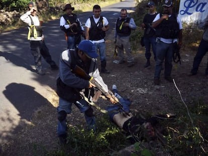 Un integrante de las autodefensas apunta al cuerpo de un 'narco' abatido