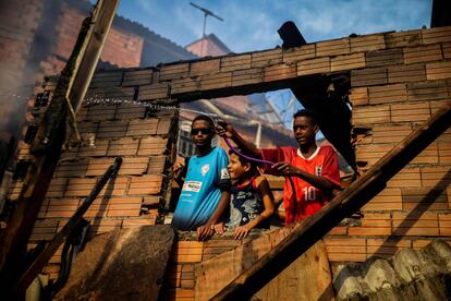 Un joven esparce agua para controlar un incendio, que destruyó medio centenar de viviendas, en Paraisópolis, la segunda mayor favela de Sao Paulo (Brasil).