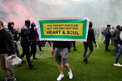 Un aficionado del United, en Old Trafford con una cartel que dice: "Tú puedes comprar nuestro club, pero no nuestro corazón y nuestra alma".