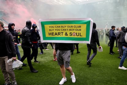 Un aficionado del United, en Old Trafford con una cartel que dice: "Tú puedes comprar nuestro club, pero no nuestro corazón y nuestra alma".