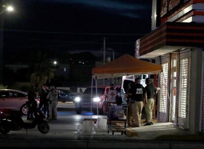 Expertos forenses afuera de la pizzería en la que fueron asesinadas cuatro personas. 