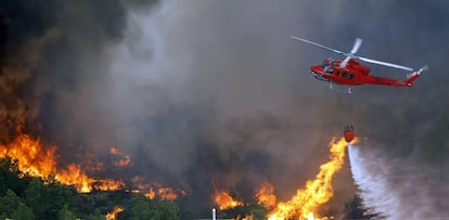 Un helicóptero descarga agua sobre el fuego en el paraje natural de La Granadella, entre los términos alicantinos de Xàbia y Benitatxell.