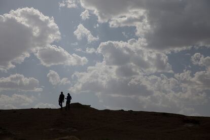Dos arqueólogos cruzan el montículo de tierra que cubre la muralla que rodeaba el sur del poblado íbero.