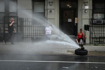 El agua de una boca de incendios refresca una calle de Manhattan en la ciudad de Nueva York (EE UU), este lunes.