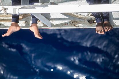 Dos migrantes descansan en un lateral del barco.
