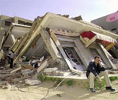 Un hombre permanece sentado delante de un edifico destruido por el terremoto en la localidad de Reghaia, en la región de Bumerdés.