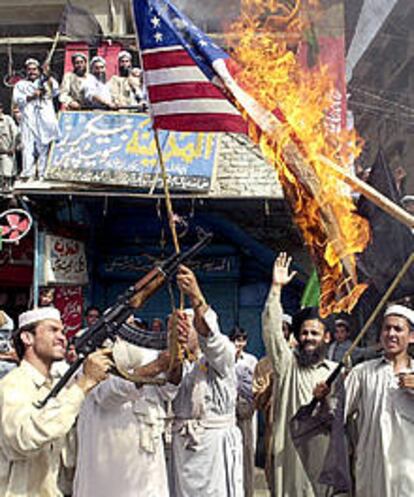 Extremistas armados paquistaníes queman una bandera estadounidense cerca de la frontera afgana.
