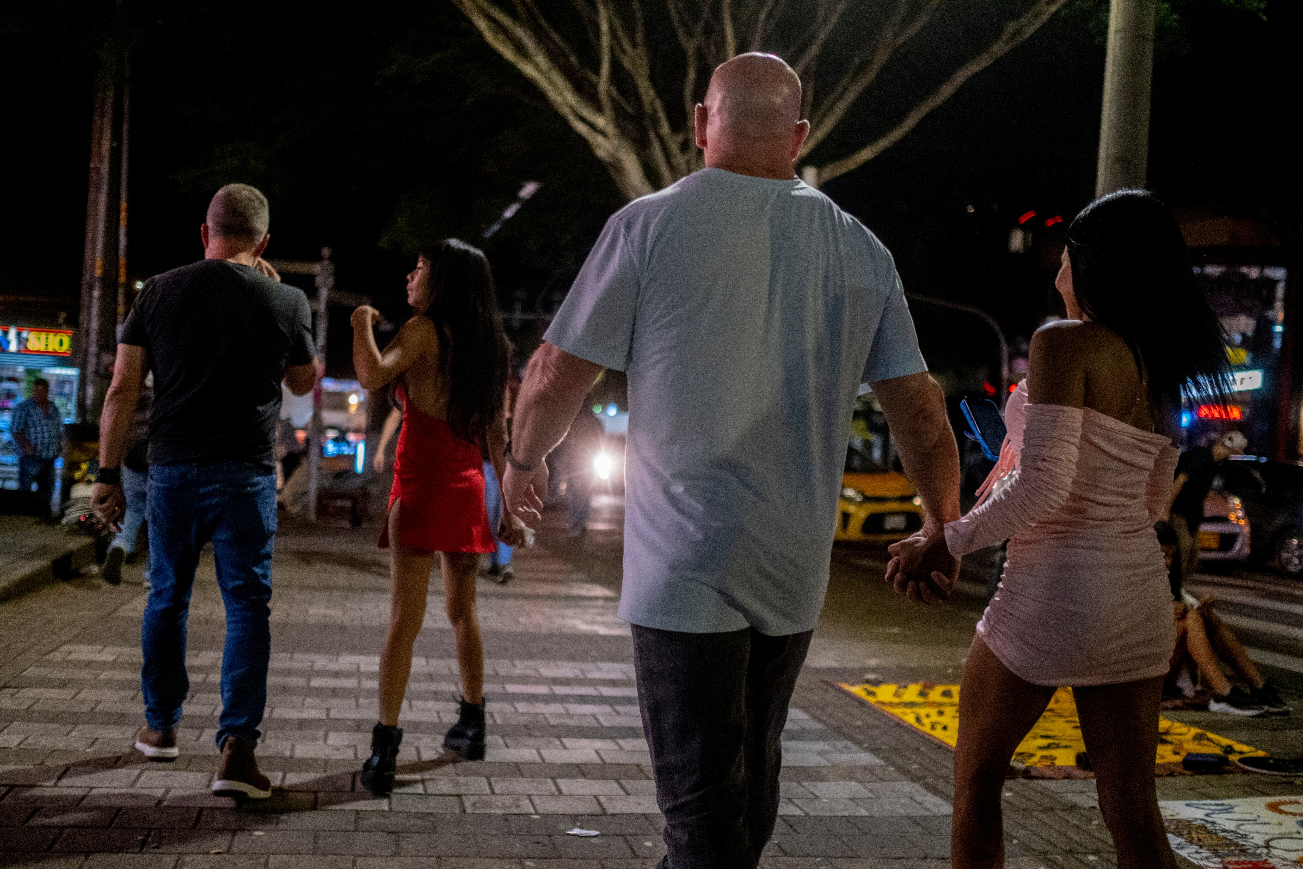 Turistas extranjeros caminan con dos mujeres en el barrio el Poblado, en  Medellín, el 29 de julio de 2022.