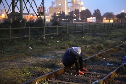 Un migrante sentado sobre las vías del tren espera a pasar el registro en el campamento de Calais. 