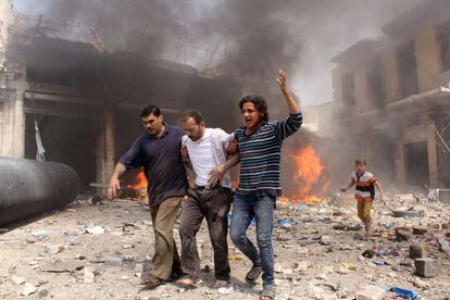 Unos hombres ayudan a un herido en un ataque con bomba sobre un mercado de la ciudad siria de Alepo.