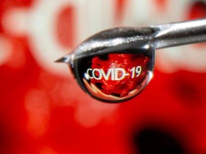 FILE PHOTO: The word "COVID-19" is reflected in a drop on a syringe needle in this illustration