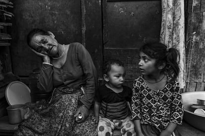 Dentro de un barrio de chabolas junto al río Bagmati, una anciana (acompañada por sus nietos) sujeta un aerosol para aliviar los dolores pulmonares que sufre. No sabe exactamente qué problema tiene y admite que a veces toma medicamentos sin ninguna prescripción médica. Reconoce sus pastillas y su aerosol solo por los colores.
