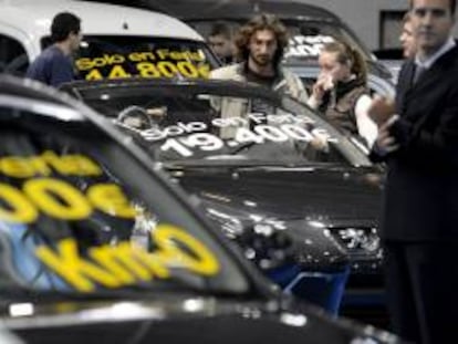 Varias personas contemplan coches de ocasión en una feria de automóviles. EFE/Archivo