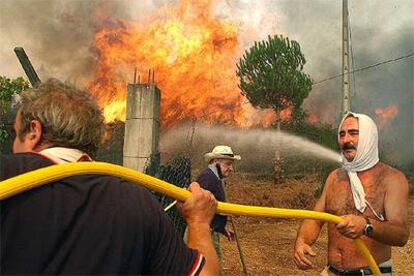 Vecinos y bomberos, durante las labores de extinción de un incendio en Velle (Ourense).