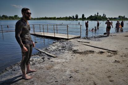 Un joven se seca al sol antes de adentrarse de nuevo en el lago a quitarse el barro.