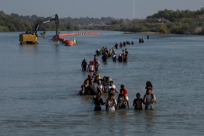 Una caravana pasa junto a una serie de boyas, que se construyen para disuadir a los migrantes de cruzar el río Grande, Texas en Estados Unidos.