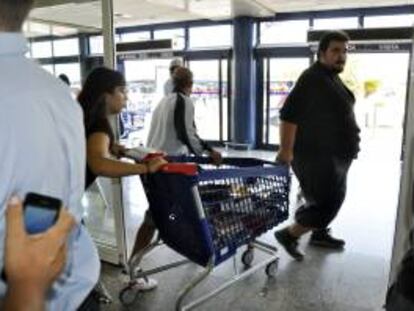 Fotografía facilitada por el SAT. Jornaleros sacan de un centro comercial diez carros llenos de material escolar. EFE/Archivo