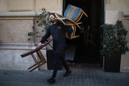 Un trabajador preparando la terraza de un restaurante en La Rambla de Barcelona.