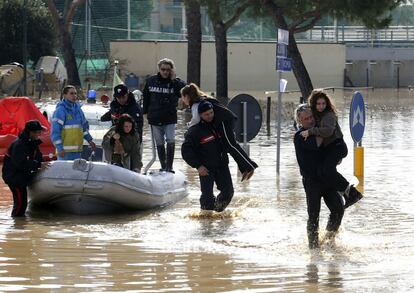 Carabineros y personal de rescate ayudan a varias personas durante la evacuación de Albinia, en el centro de Italia.