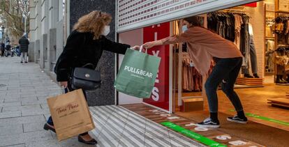 Una clienta recoge una bolsa de manos de una dependienta en un comercio del centro de Barcelona, este jueves en Cataluña.  